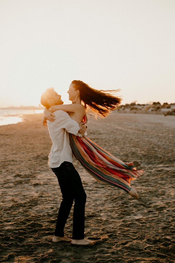 le marié porte la mariée et la fait tourner pour la séance photo couple à la plage