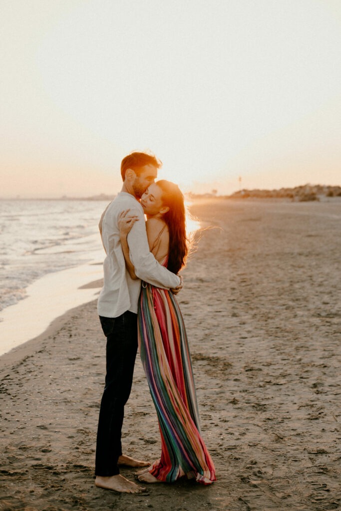 un couple s'embrasse à la plage, au bord de l'eau à la golden hour