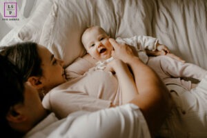 bébé souriant, allongé sur le lit de ses parents faisant un calin