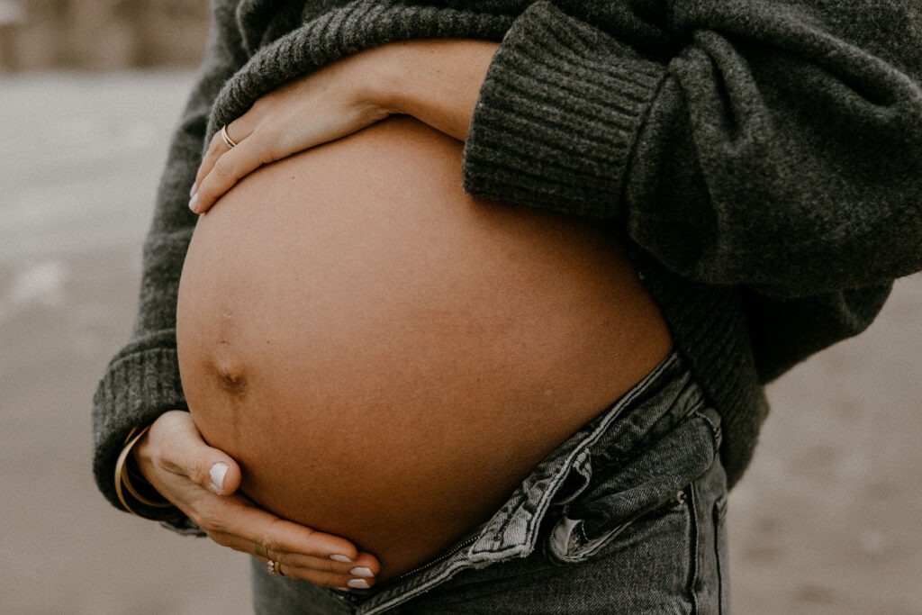 gros plan sur le ventre d'une future maman pendant sa séance photo à la plage l'hiver à montpellier