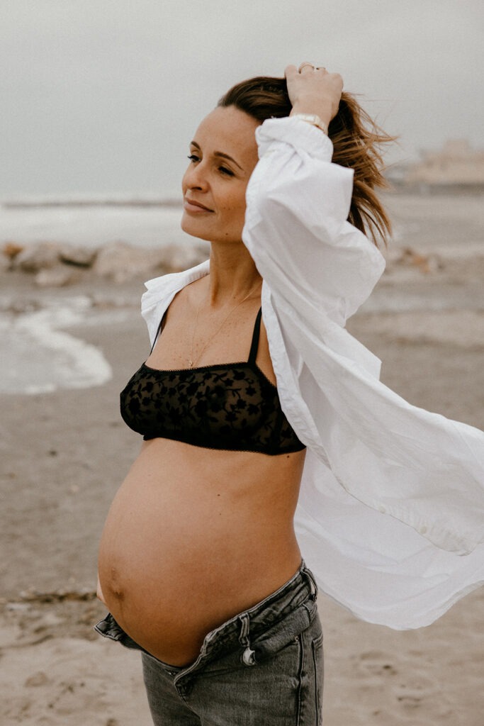 future maman qui marche au bord de l'eau pour sa séance photo grossesse l'hiver à la plage